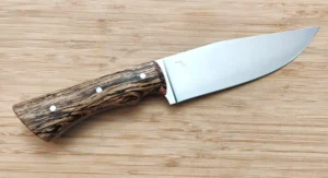 Full right view of the Bur Oak Camper/Chopper knife with a 6 1/4" brushed clip point blade made of 1095 high carbon steel and a stabilized Florida bur oak handle with mild steel pins, placed on a wooden surface.