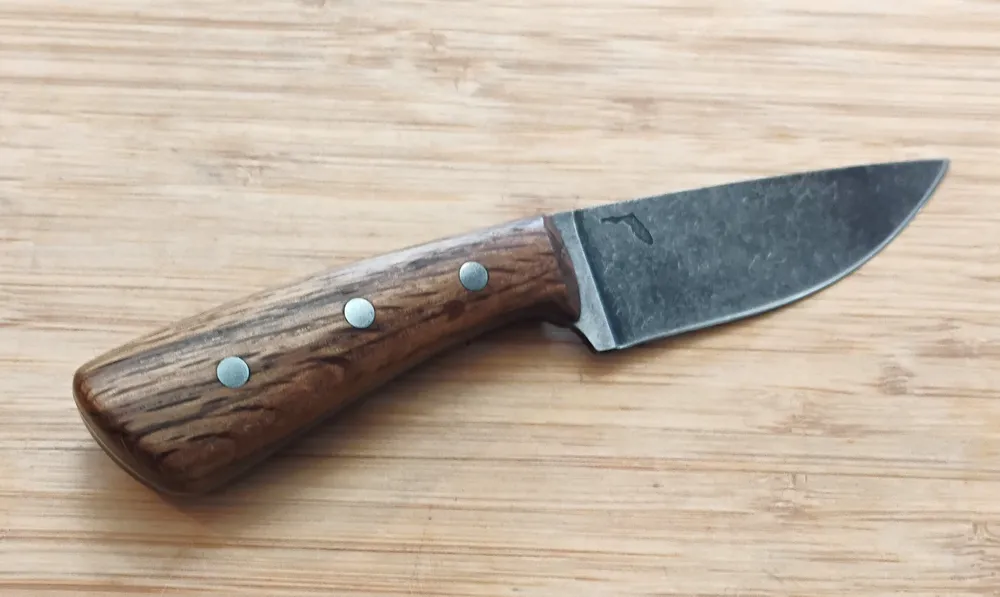View of right side of Bur Oak Caping Knife #334 with stabilized Oak handle and mild steel pins on bamboo background