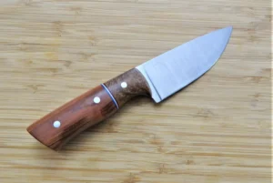 Right side of Wild Plum Little Camper #185 Knife showcasing mild steel pins and Pecan bolster, on wooden surface