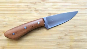 Wild Black Cherry Goldilocks #211 drop point EDC knife, full right view, 1095 steel blade, wild black cherry wood handle on wooden surface