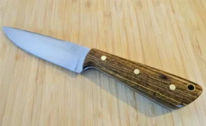Bocote Drop Point #67 knife with an exotic wood handle, brass pins, and a polished steel blade, crafted by GreBec Knives, on a wooden surface.