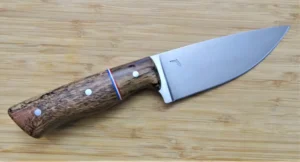 Right side of Burr Oak Spalted Pecan Big Camper Knife showcasing mild steel pins and Spalted Pecan bolster, on wooden surface