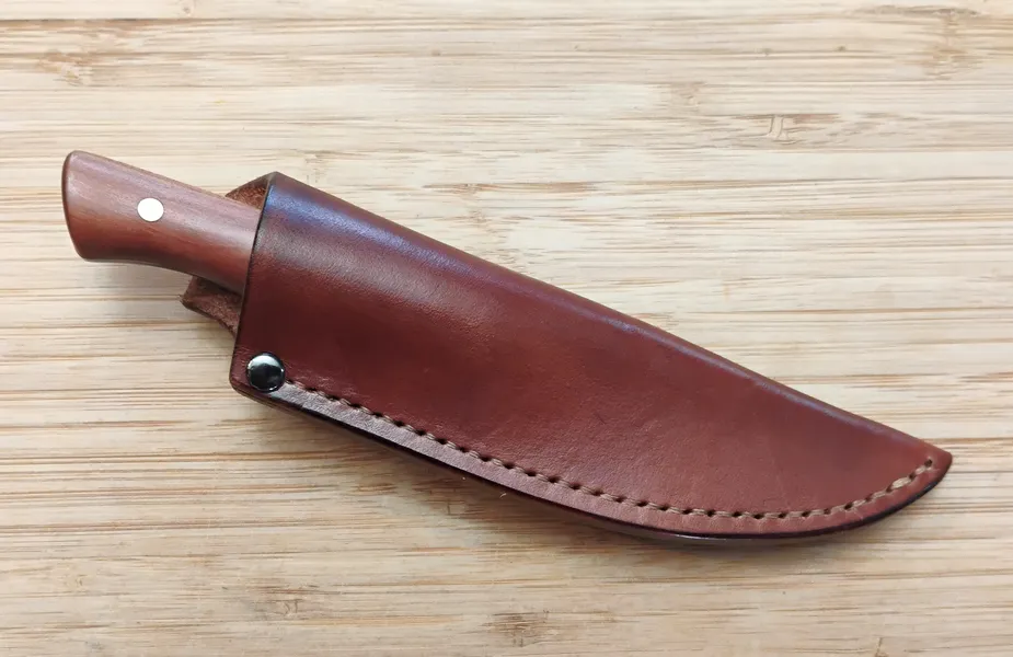 Red Cedar Bird and Trout Knife in the custom leather sheath, on wood.