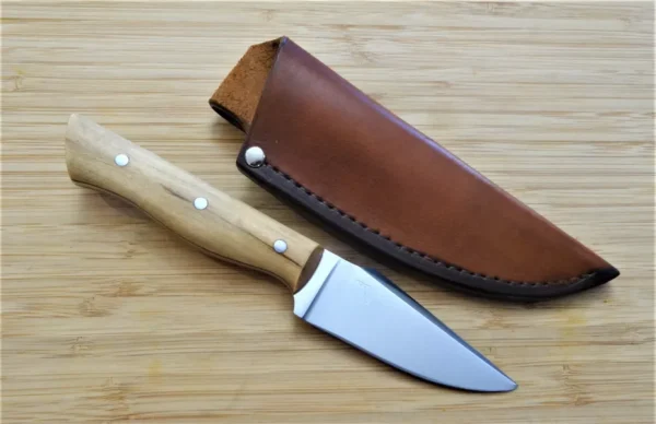 Custom Palatka Holly Harpoon clip point #211 EDC next to a hand cut and dyed two tone pouch sheath on a wood surface