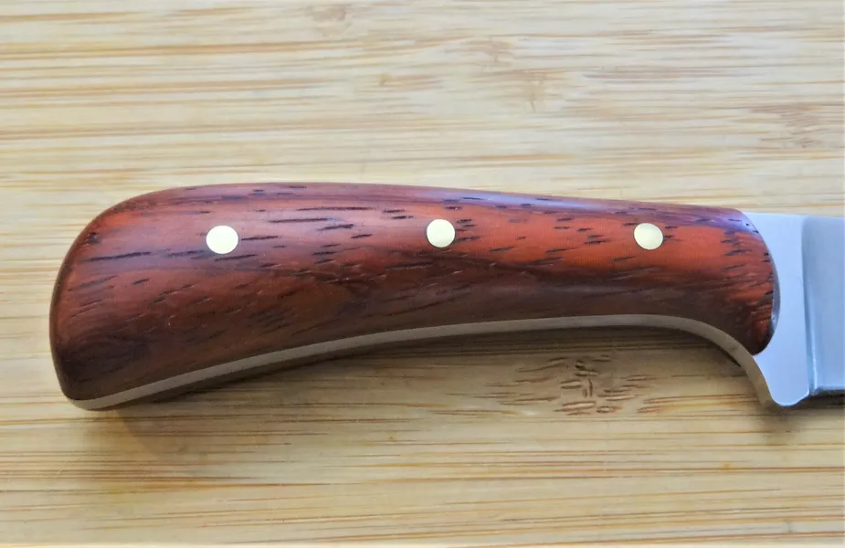 Right handle closeup of a Padauk upswept clip point made from 1095 high carbon stell