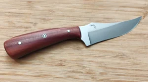 Handcrafted Red Cedar Trailing Point #315 knife with a unique sapwood-accented wood handle and high-carbon steel blade on a bamboo cutting board