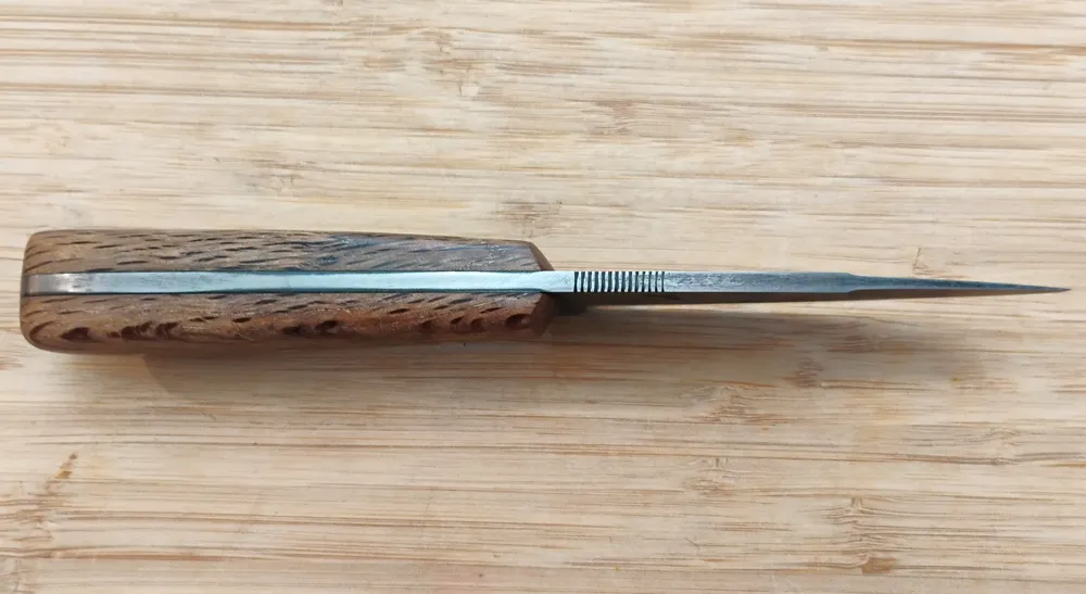 Spine view of an EDC/Hunter knife with a 1 7/8” swedge on a 1095 high carbon steel blade, featuring thumb serrations