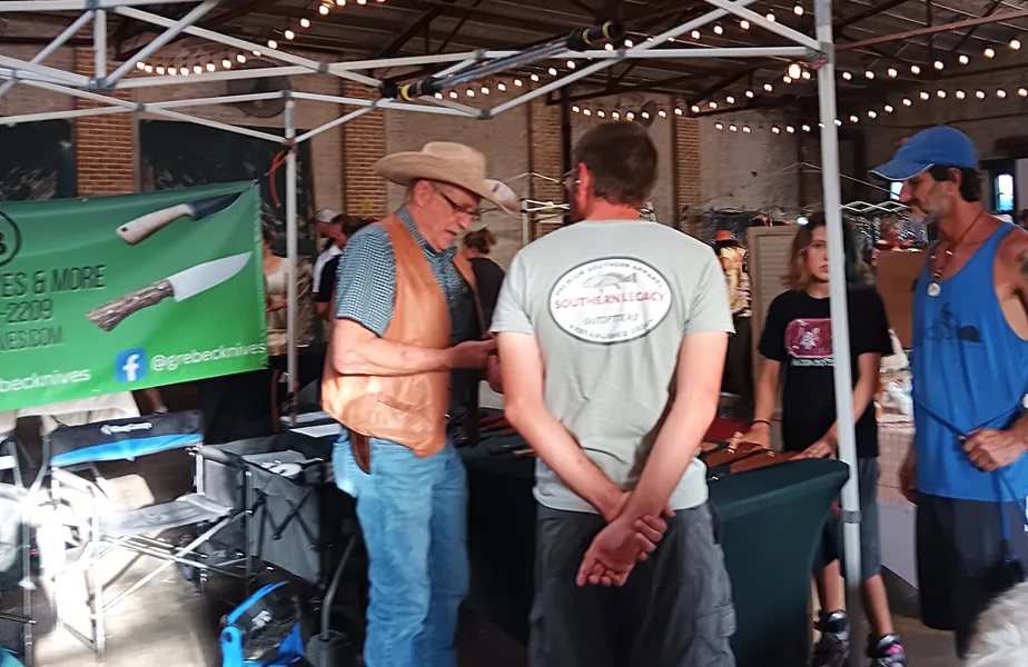 Greg showing knives to customers at the table for DeLand Artisans market