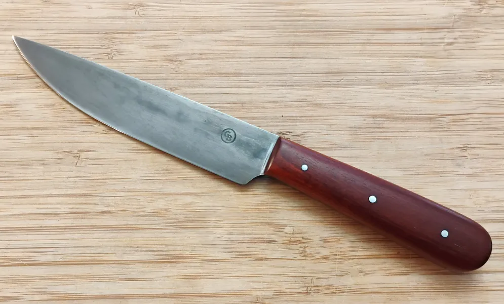 High carbon steel 1800's Trade Knife left side view displaying a drop point blade and stabilized handle on a wooden background