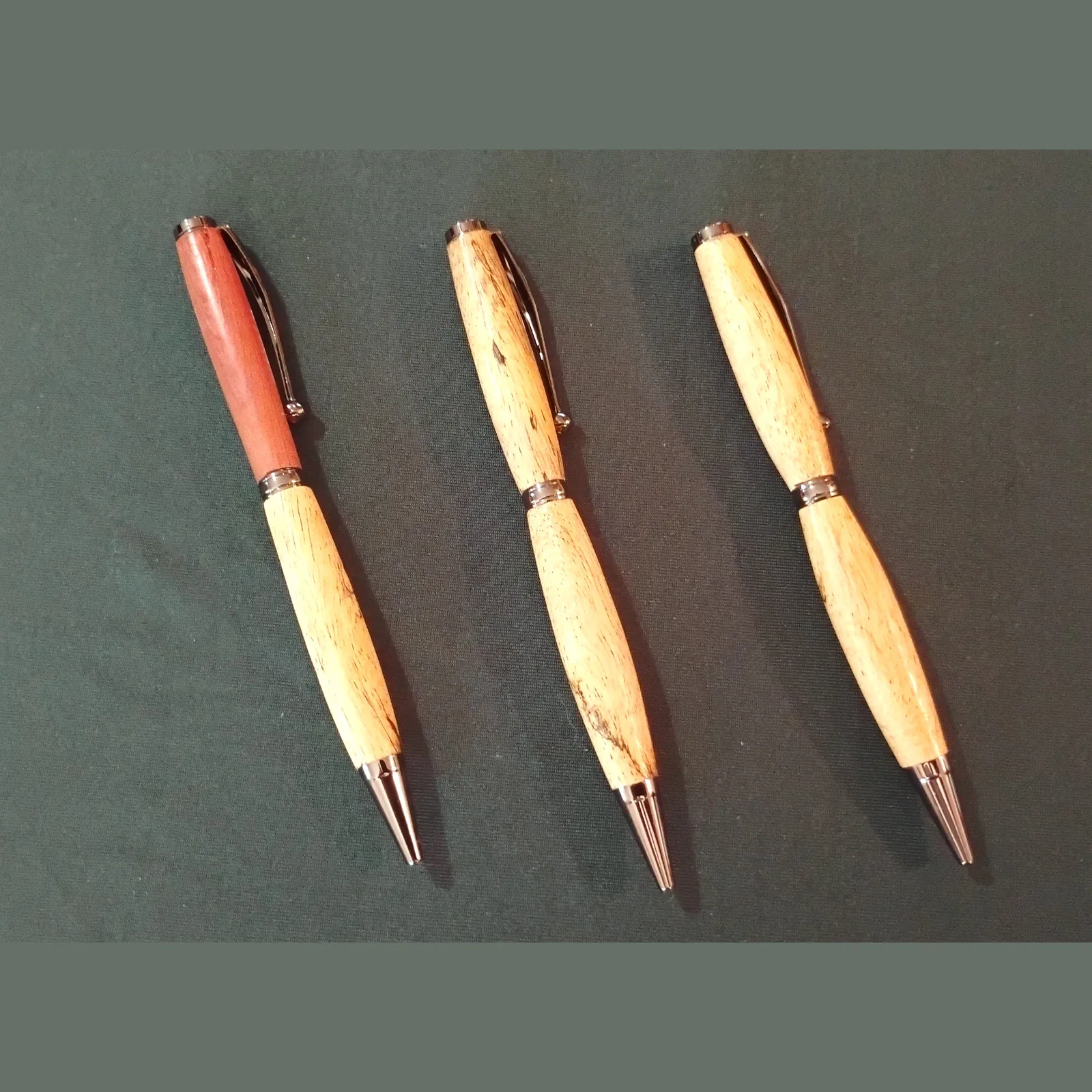 Three hand turned pens on green background for DeLand Artisans Market 10/3/25