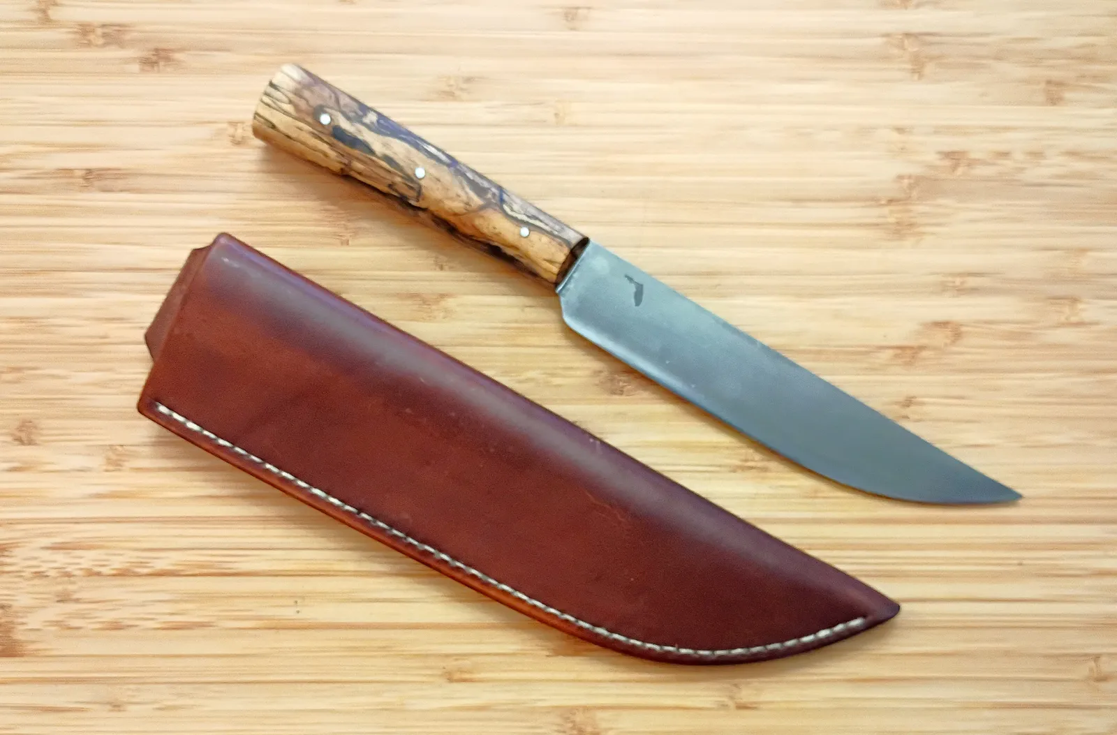 English trade knife beside oak bark–dyed leather sheath with historic natural finish