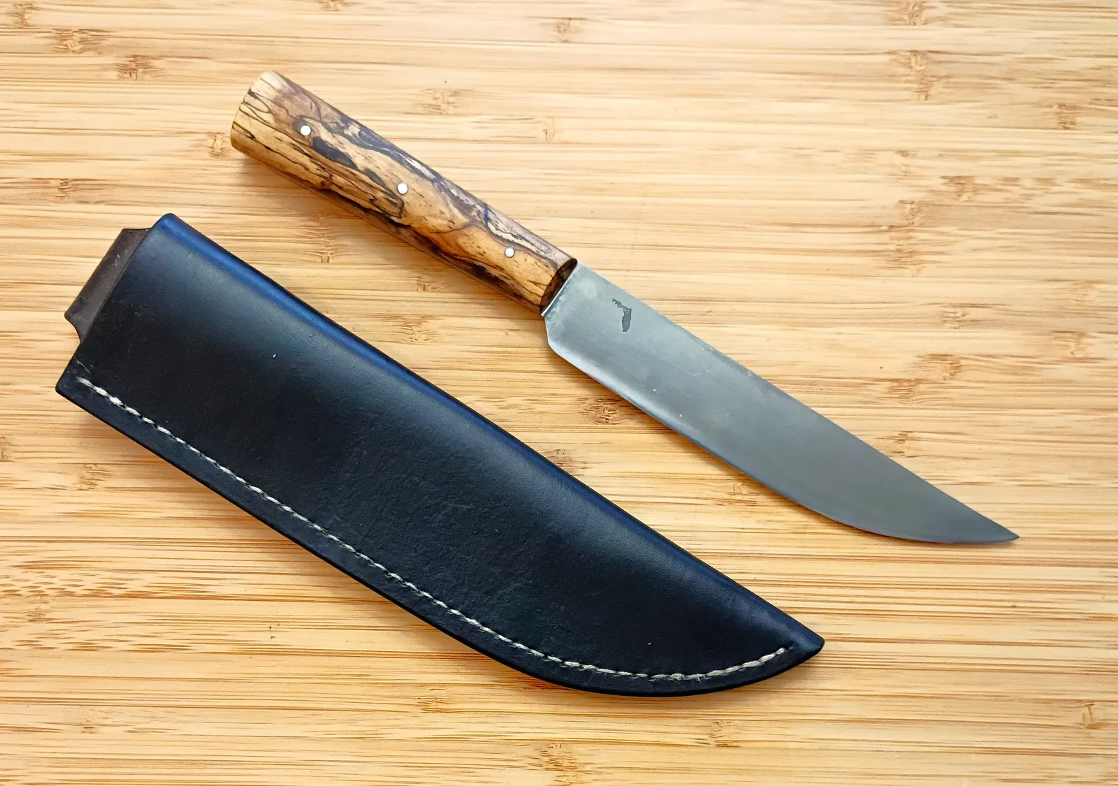 English trade knife beside handcrafted vinegaroon-dyed leather sheath by GreBec Knives