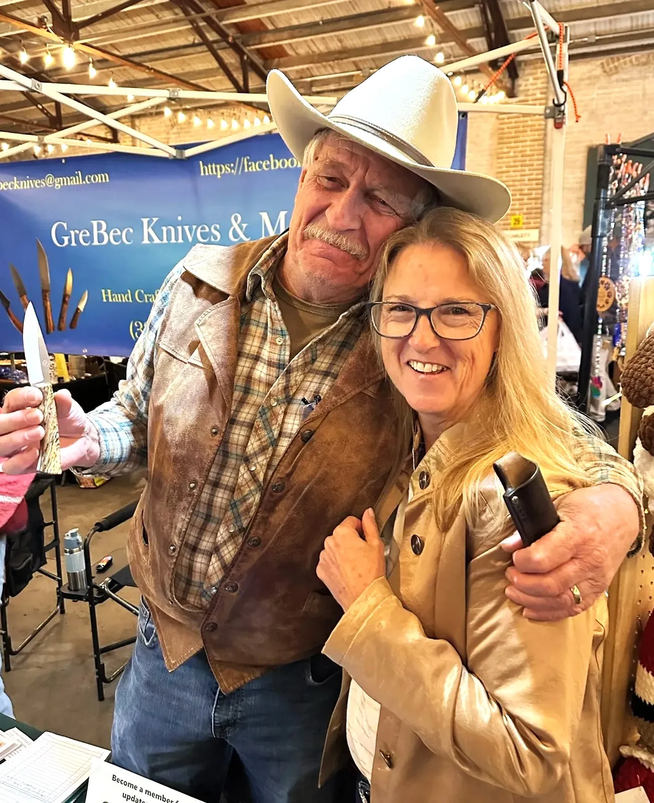 Greg holding a new Harpoon Clip Point knife with spalted pecan handle with female purchaser standing next to him at DeLand Artisans Market.