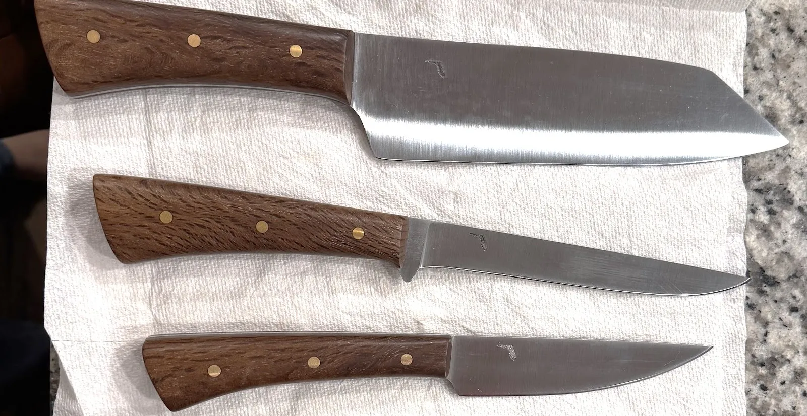 Three custom made GreBec Knives high carbon steel kitchen knives with stabilized Live Oak handles and brass pins.