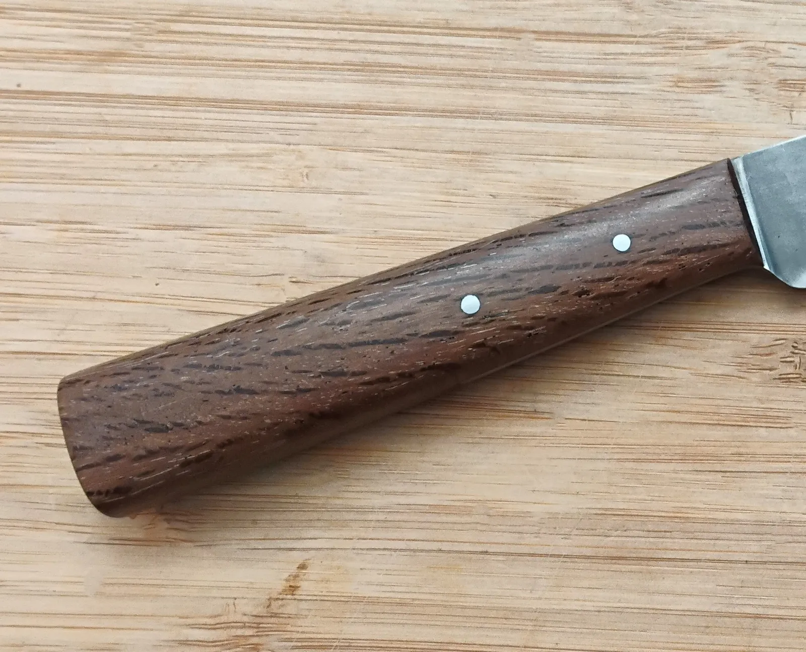 Closeup view of a Florida Live Oak knife handle with dark brown wood and black grain pattern on a custom made 1/2 tang historic trade knife.