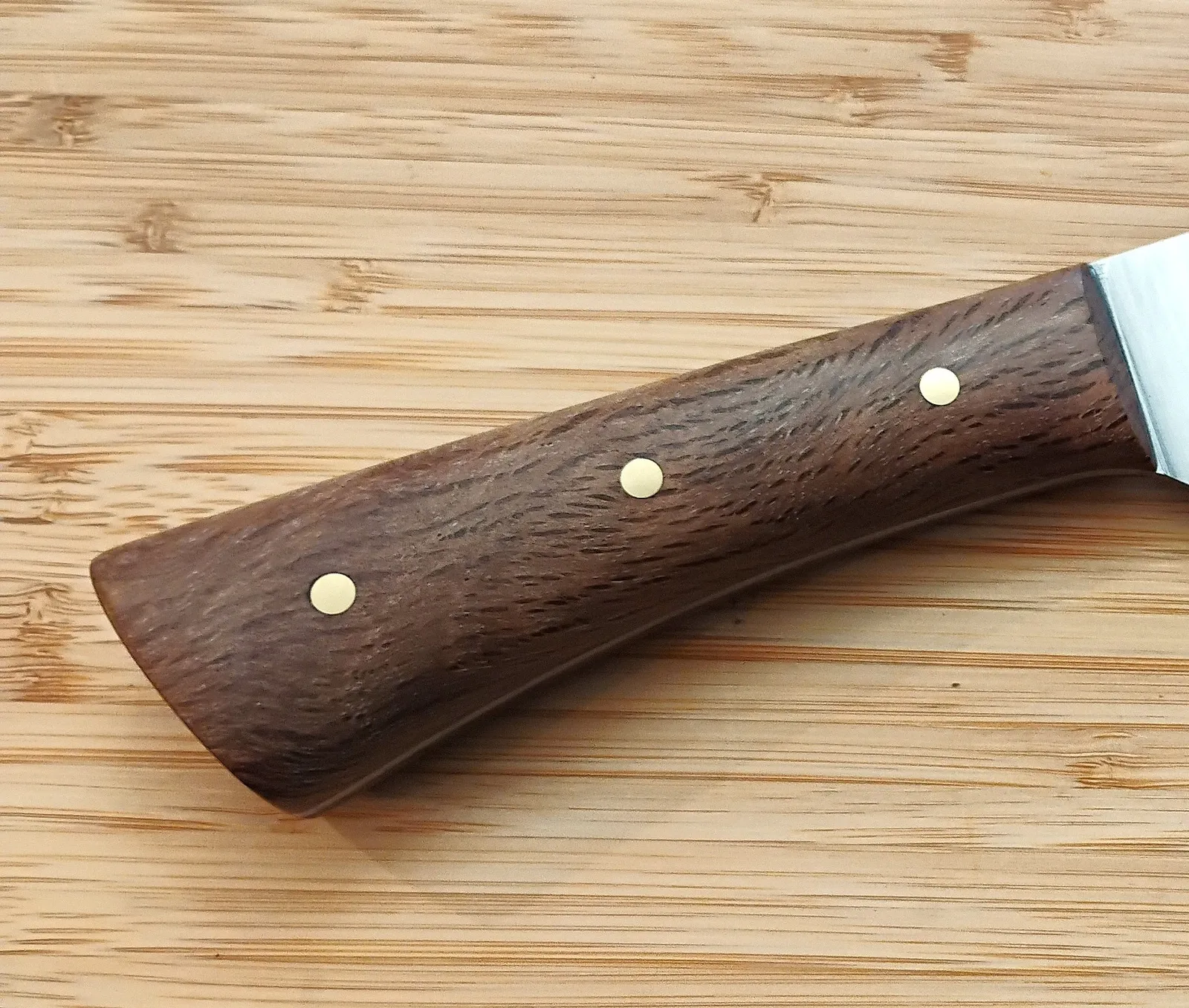 Stabilized Florida Live Oak knife handle on a handmade high carbon steel Chef knife with brass pins on a bamboo background.