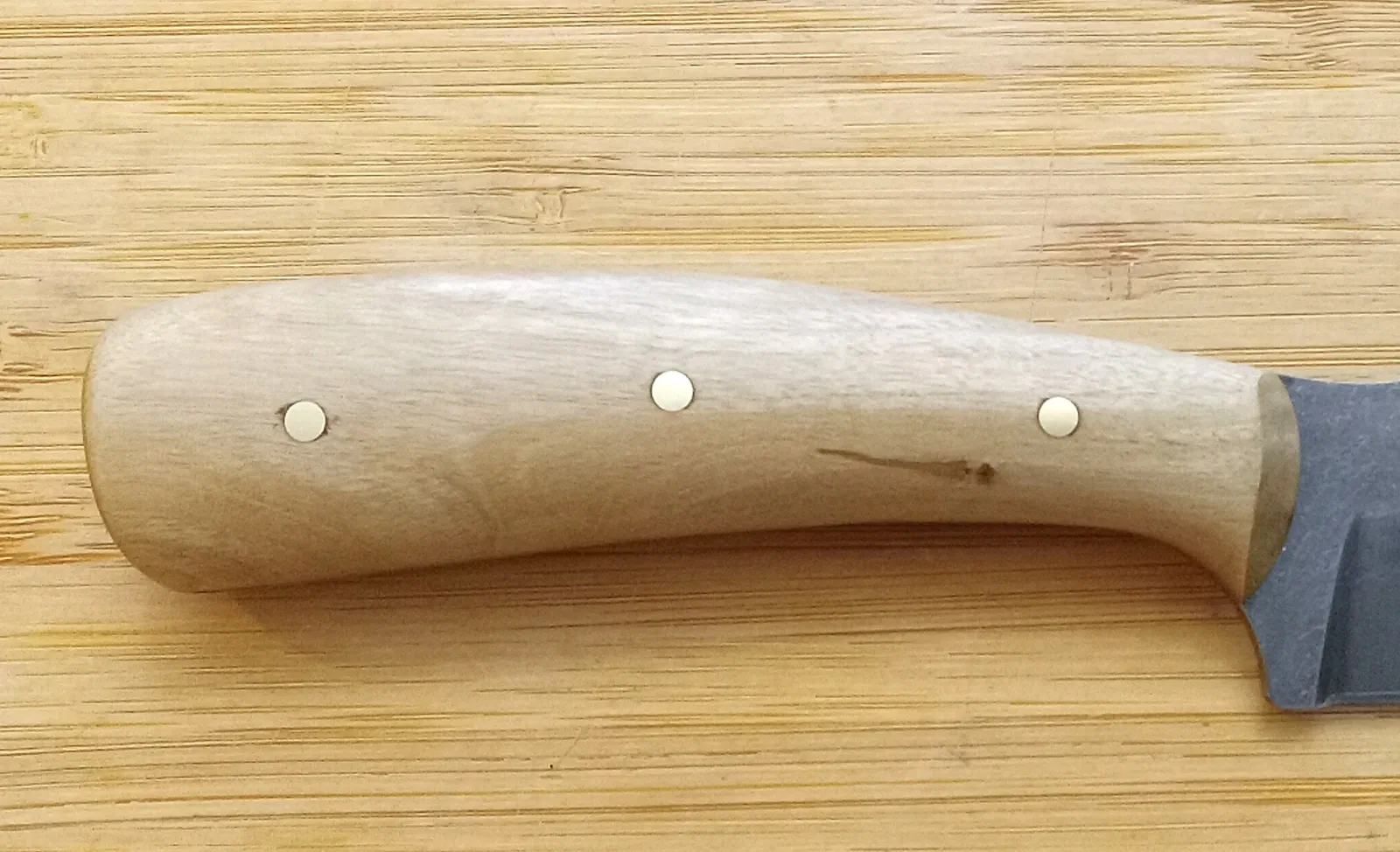 Right view of a custom Crepe Myrtle knife handle with brass pins on a bamboo background.
