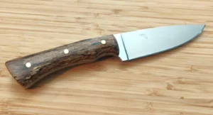 Close view of the handcrafted Goldilocks Refined Grip knife featuring a brushed blade, figured Bur Oak handle scales, thumb jimping, and brass pin accents.