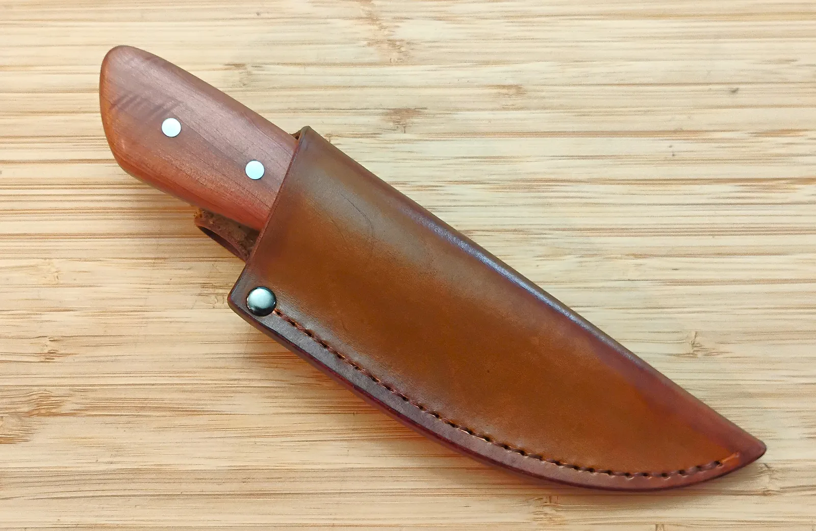 Red Cedar 3 Finger Skinner #473 partially inserted into its custom brown leather pouch sheath.