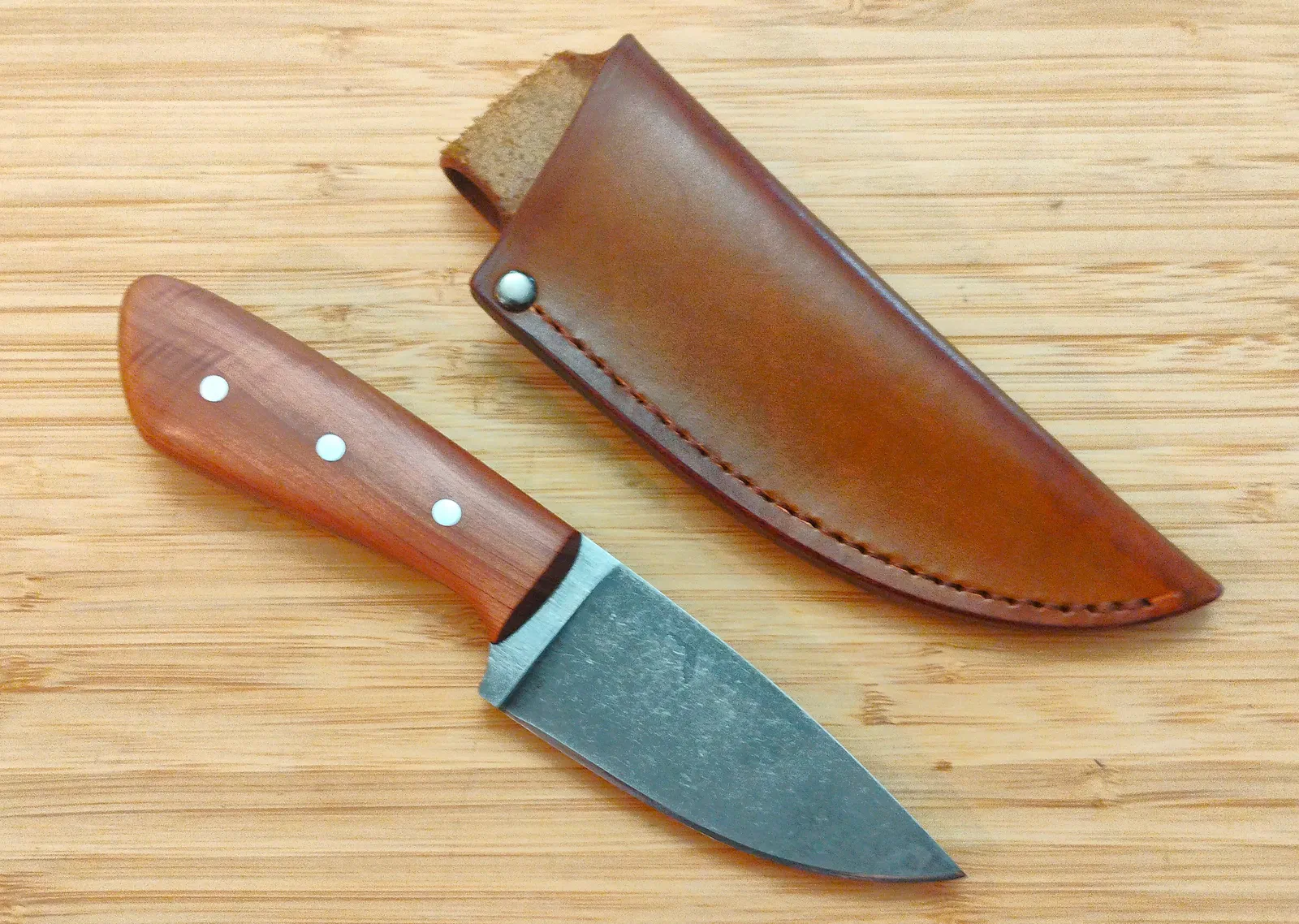 Red Cedar 3 Finger Skinner #473 displayed beside its handcrafted brown leather sheath.